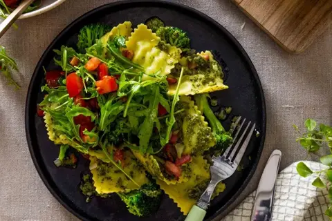 Ravioli i pesto med bacon, broccoli og tomatsalat