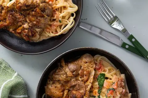 Citruskrydret kyllingelårsteak og pasta i cremet sauce med spinat og tomat