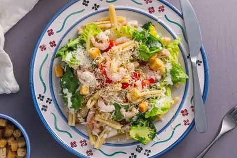 Pastasalat med rejer, broccoli og cæsardressing, toppet med croutoner