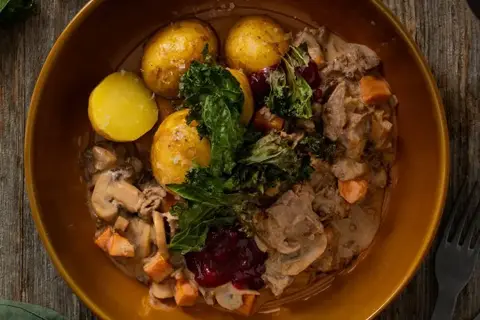 Krondyrragout med smag af Karl Johan-svampe, serveret med rørte tyttebær og sprød grønkål
