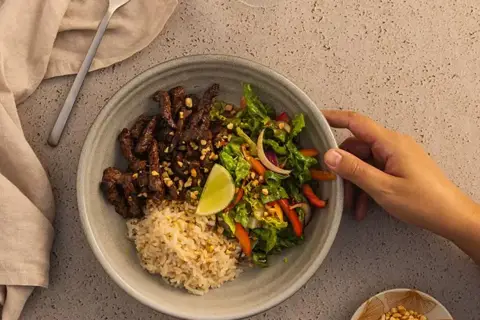 Thaisalat med oksetykstegsbøffer og friske grøntsager, serveret med peanuts og fuldkornsris