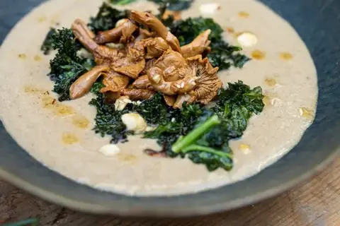 Svampesuppe toppet med smørstegte kantareller, sprød grønkål og hasselnødder