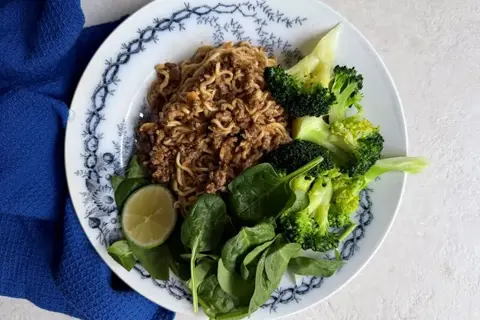 Nudler med krydret oksekød, peanutsauce og broccoli