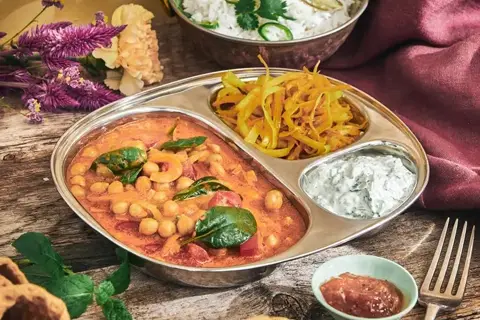 Indisk punjabi thali med chana masala, pulao og raita