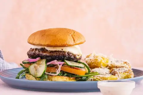 Trøffelburger med mozzarella, smashede krydderkartofler, syltet agurk, rucola og tomat