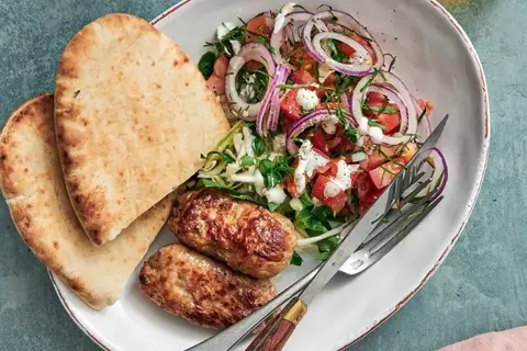 Italiensk salsiccia-kebab i pitabrød med citronmarineret kål og tomatsalat